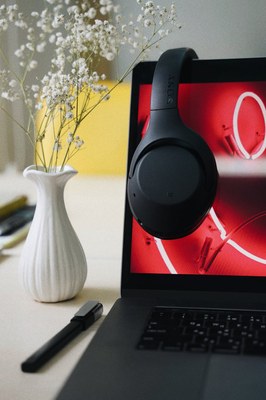 Das Foto zeigt einen aufgeklappten Laptop mit darüberhängendem Kopfhörer.